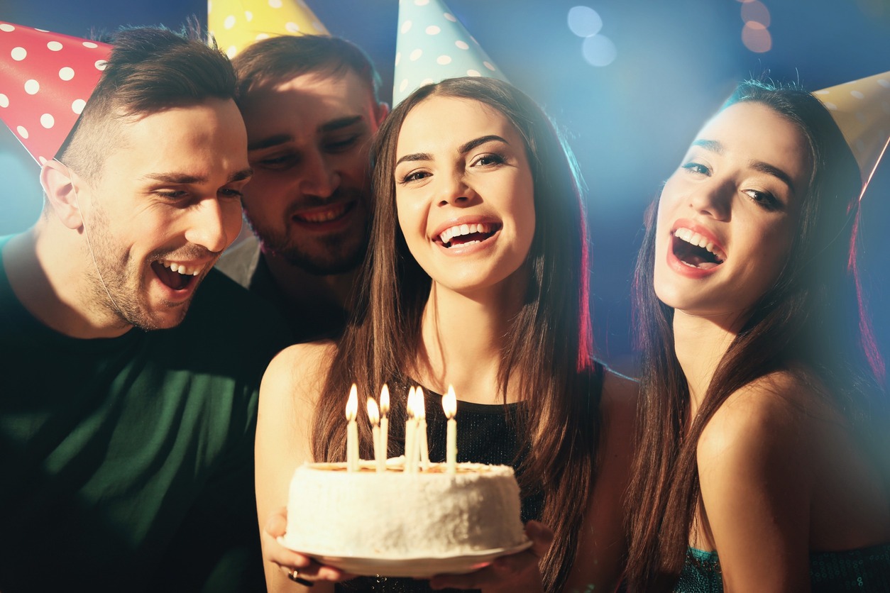 jovenes felices celebran cumpleaños frente a tarta